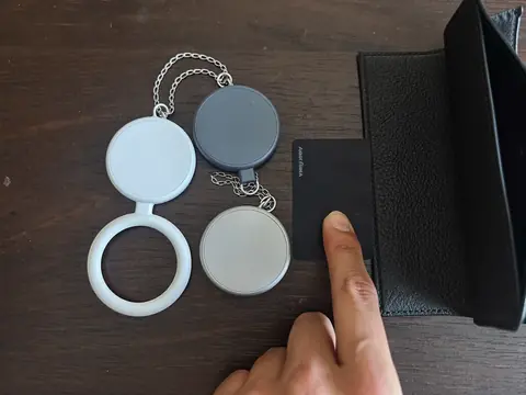 Round keyring trackers next to the flat Arqellio card